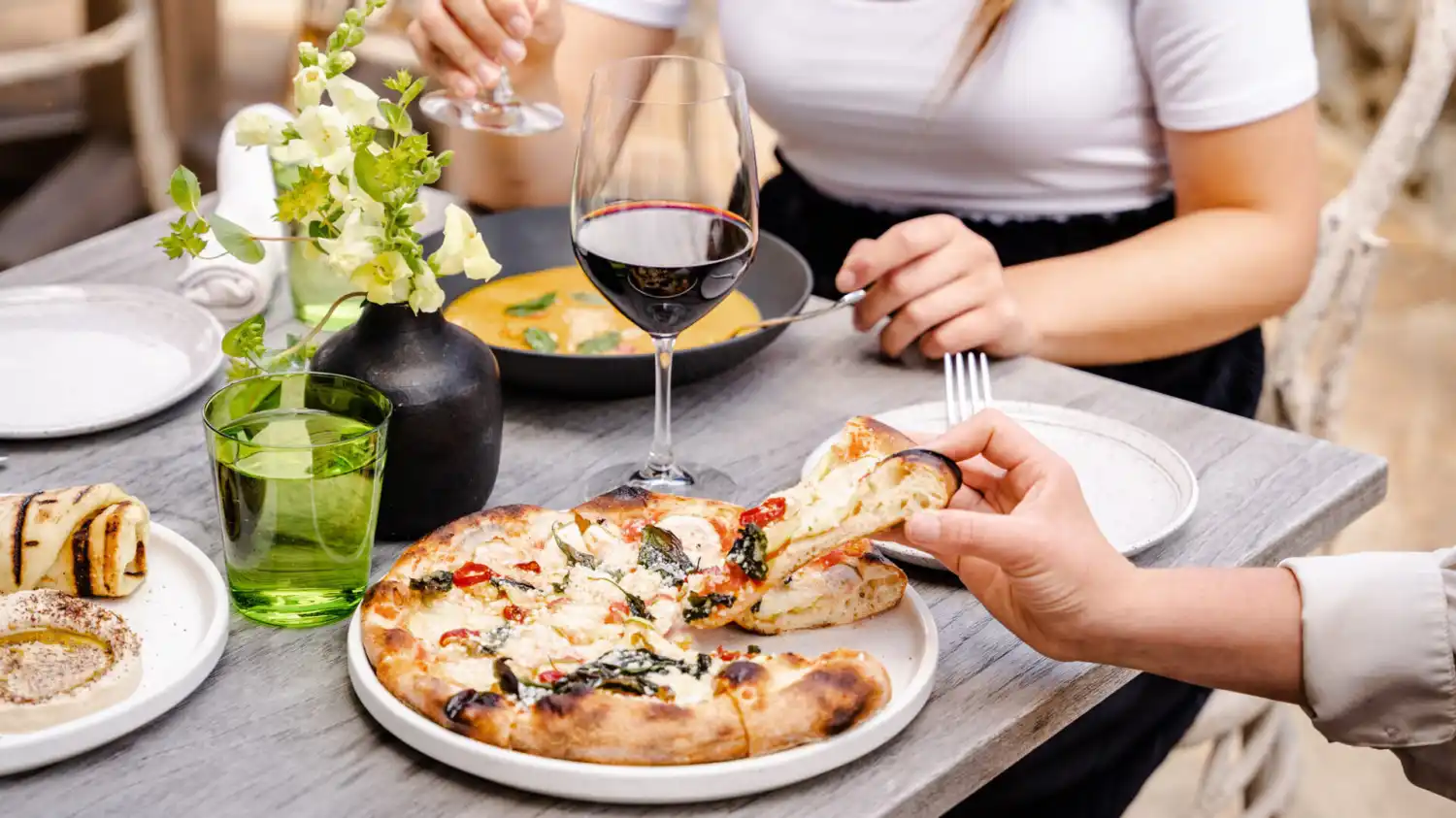 People enjoying flatbread, soup and wine at a dining table