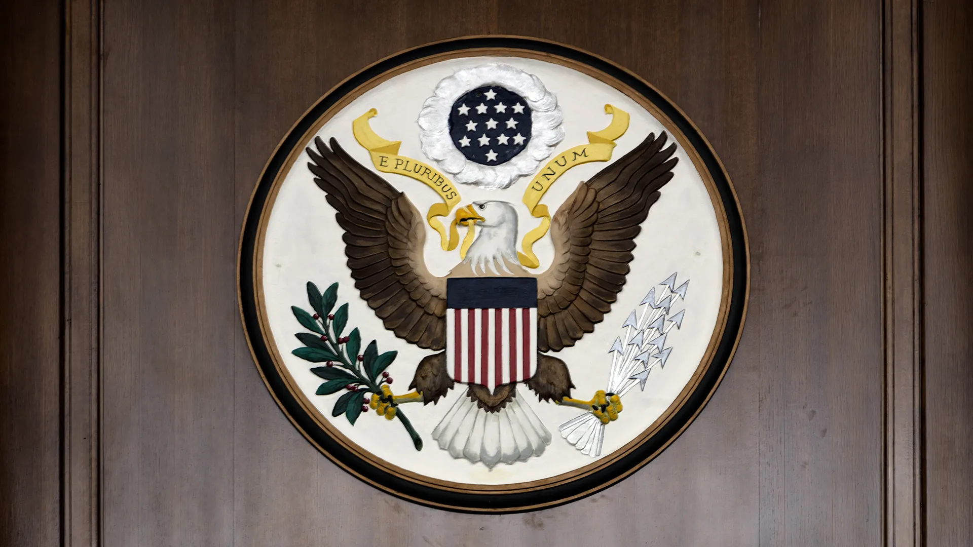 The Great Seal of the United States showing a bald eagle holding arrows and an olive branch.