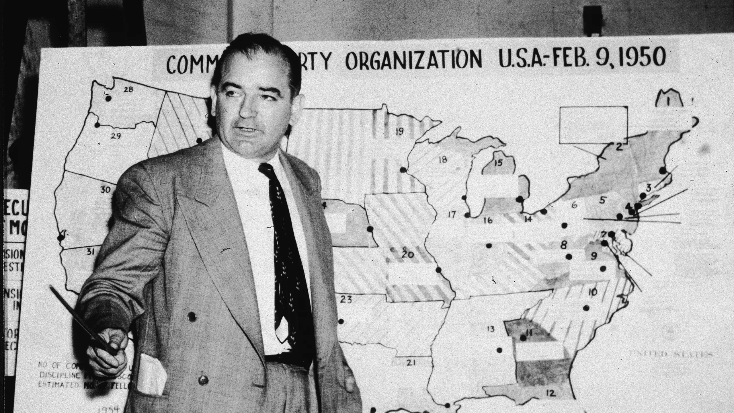 Senator Joseph McCarthy brandishing a list of supposed communists in the U.S. government, igniting a nationwide frenzy of suspicion and fear.