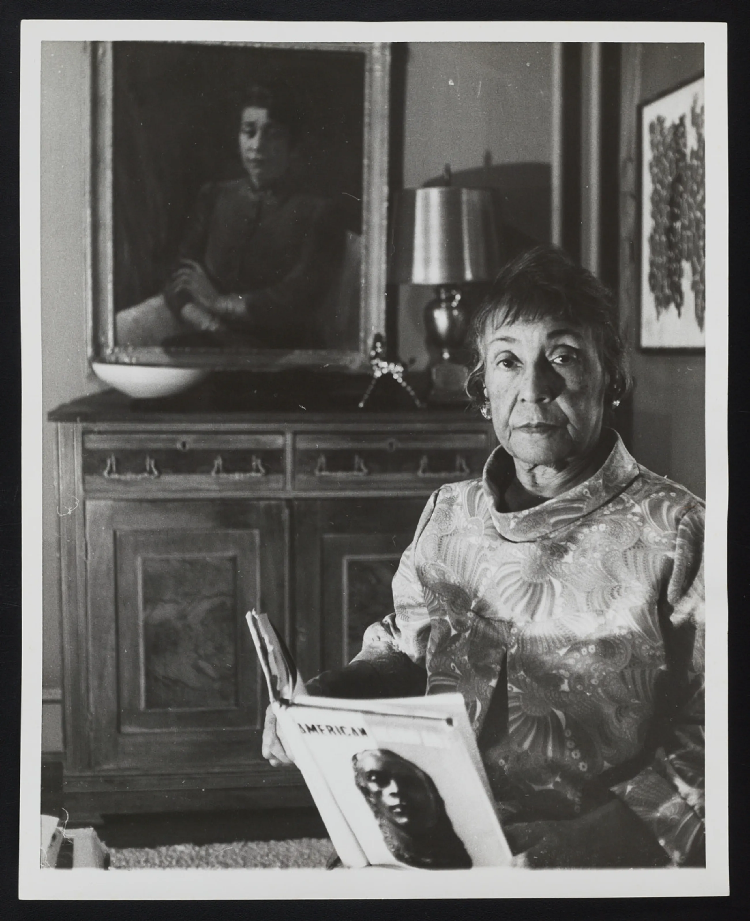 Portrait of Alma Thomas smiling, surrounded by swatches of colorful paint in her home studio.