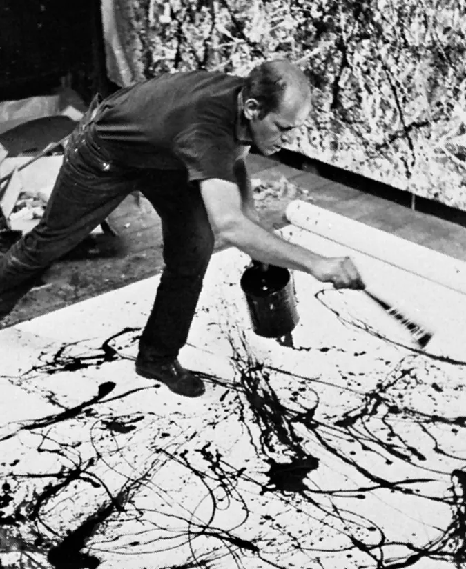 Portrait of Jackson Pollock, intense gaze with paint-splattered clothes in his Long Island studio.
