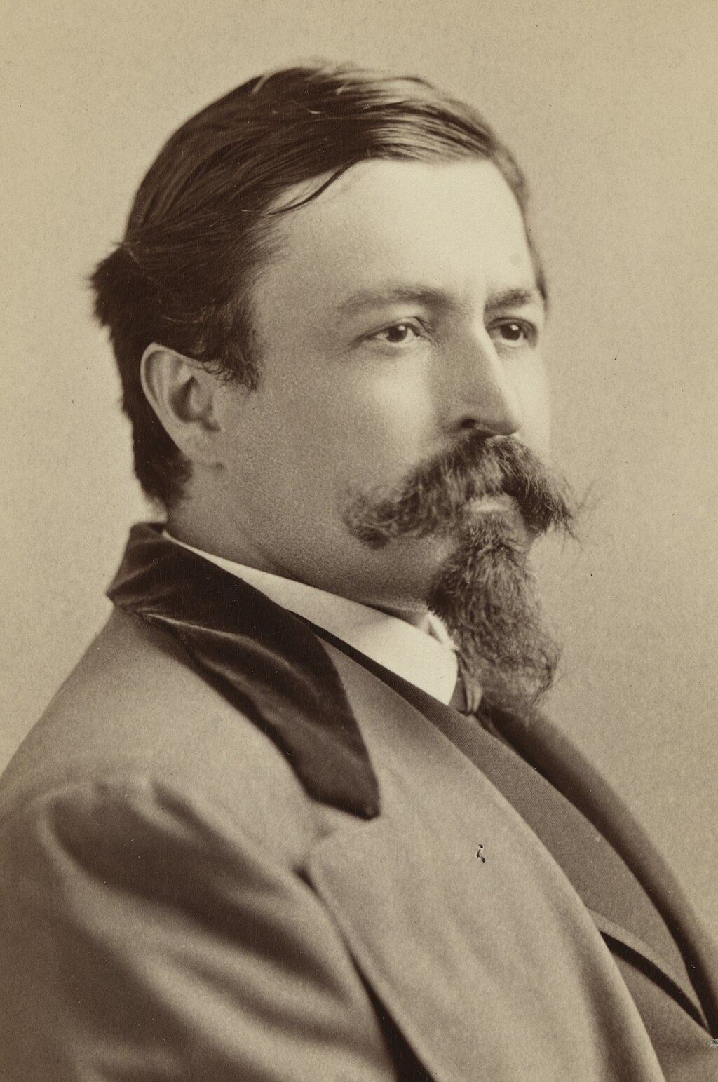 A black-and-white portrait of Thomas Nast, holding a pen and sitting at a drawing board with sketches in progress.