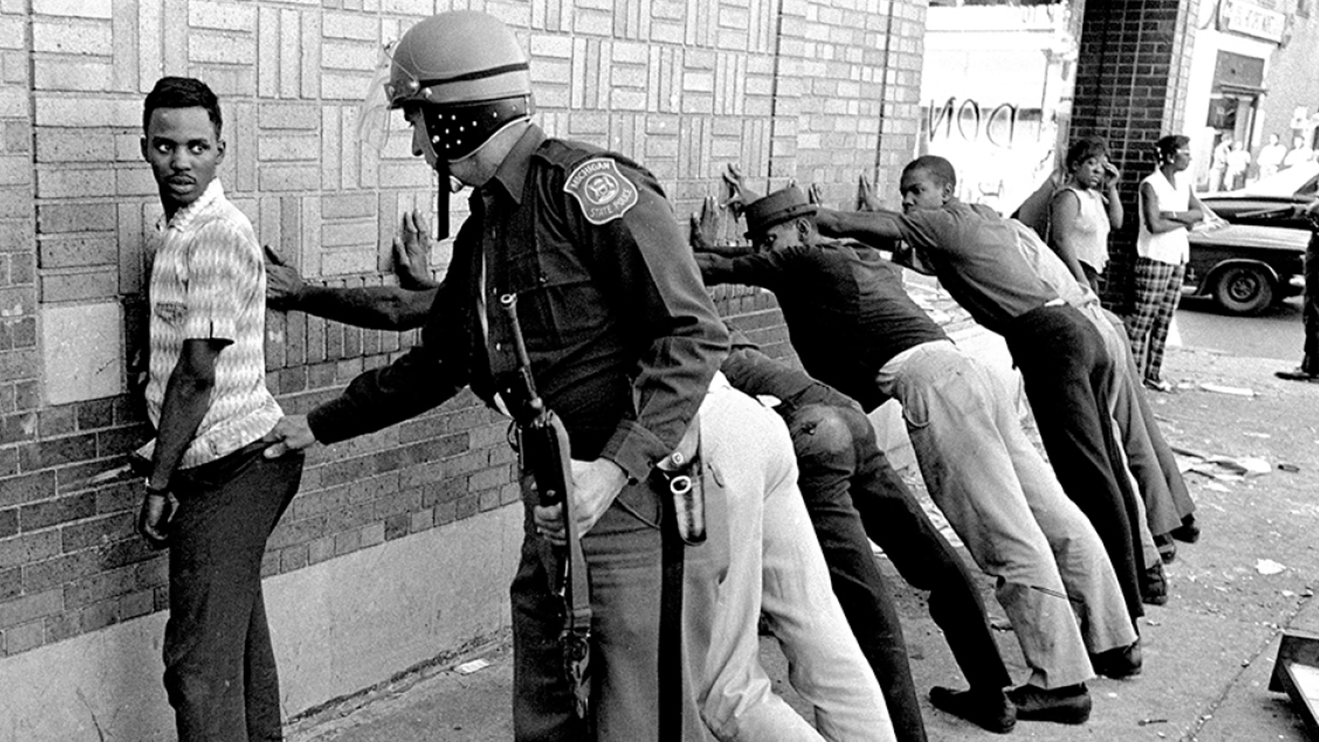 National Guard troops and tanks patrol the streets of Detroit amid smoke, rubble, and burnt-out buildings during the 1967 uprising.