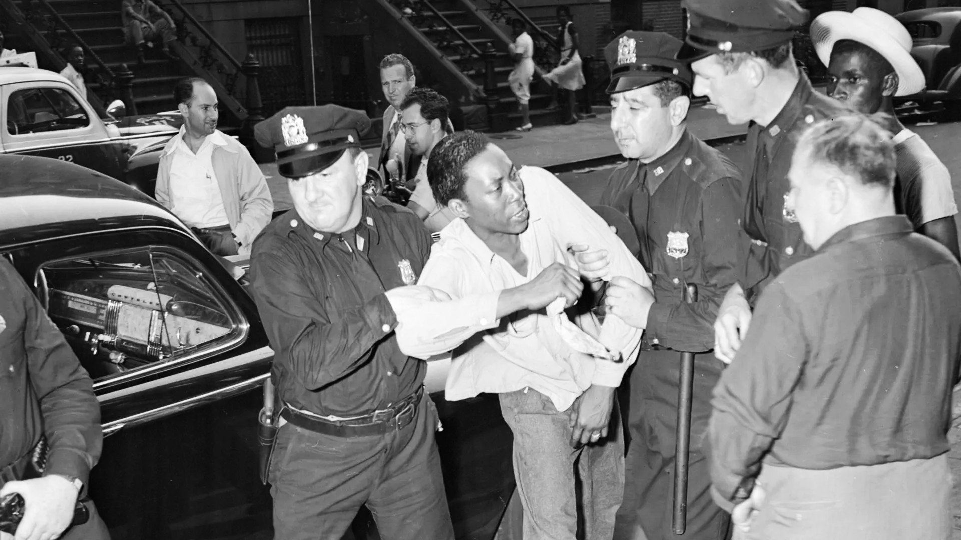 Black residents gather on Harlem streets as police patrol during the 1943 riots.