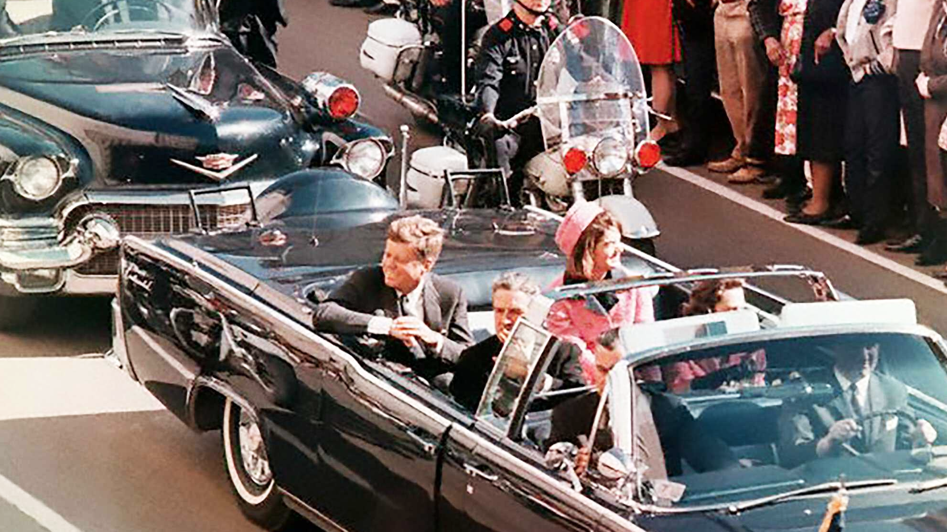 President John F. Kennedy and First Lady Jacqueline Kennedy riding in an open car in Dallas shortly before the assassination.