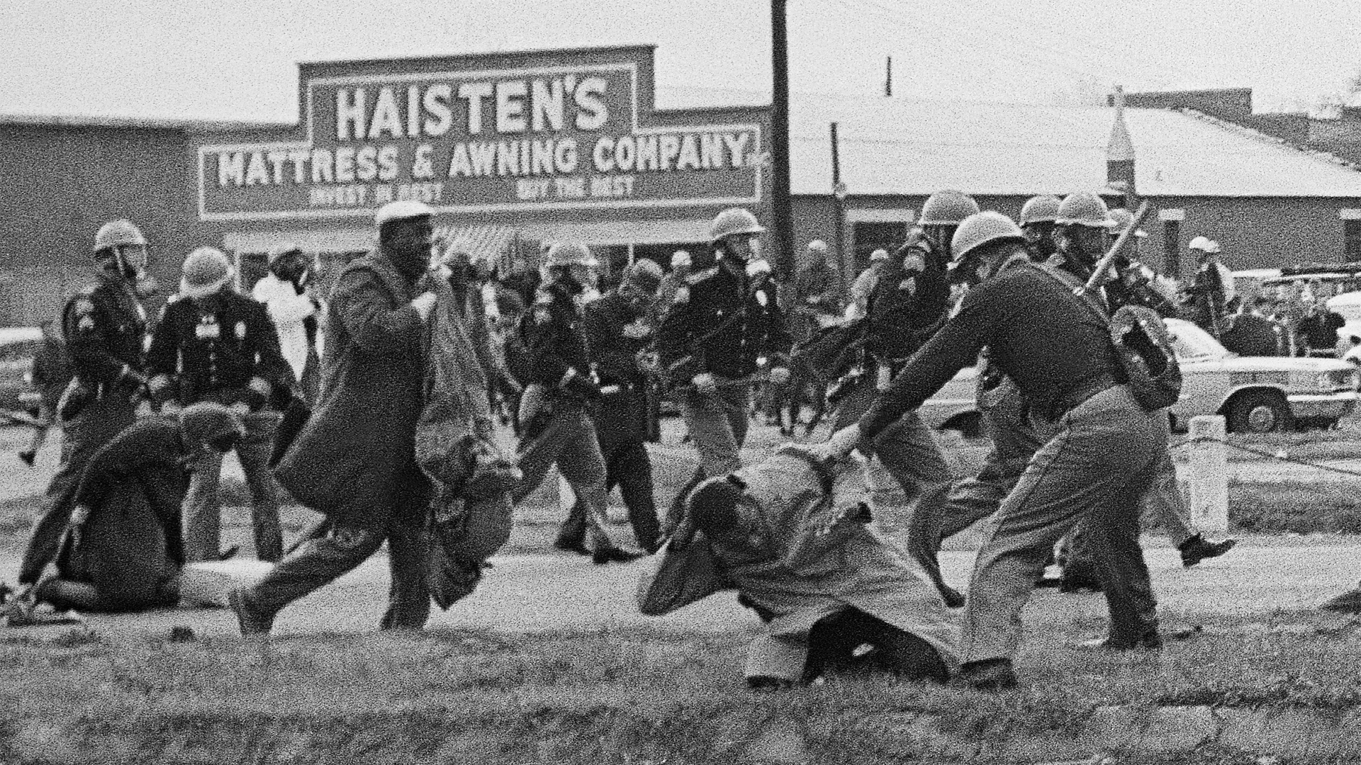 Civil rights marchers getting attacked by state troopers with billy clubs.