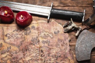 Treasure map of ancient lands. Ancient journey concept. Old map and battle axe on the wooden flat lay table background.