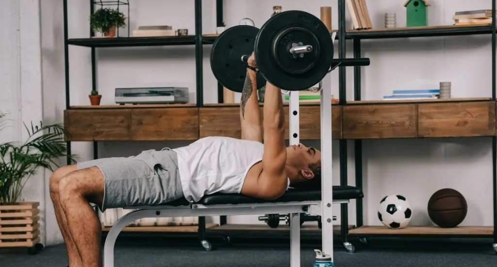 Entrepreneur bench pressing in custom built home gym