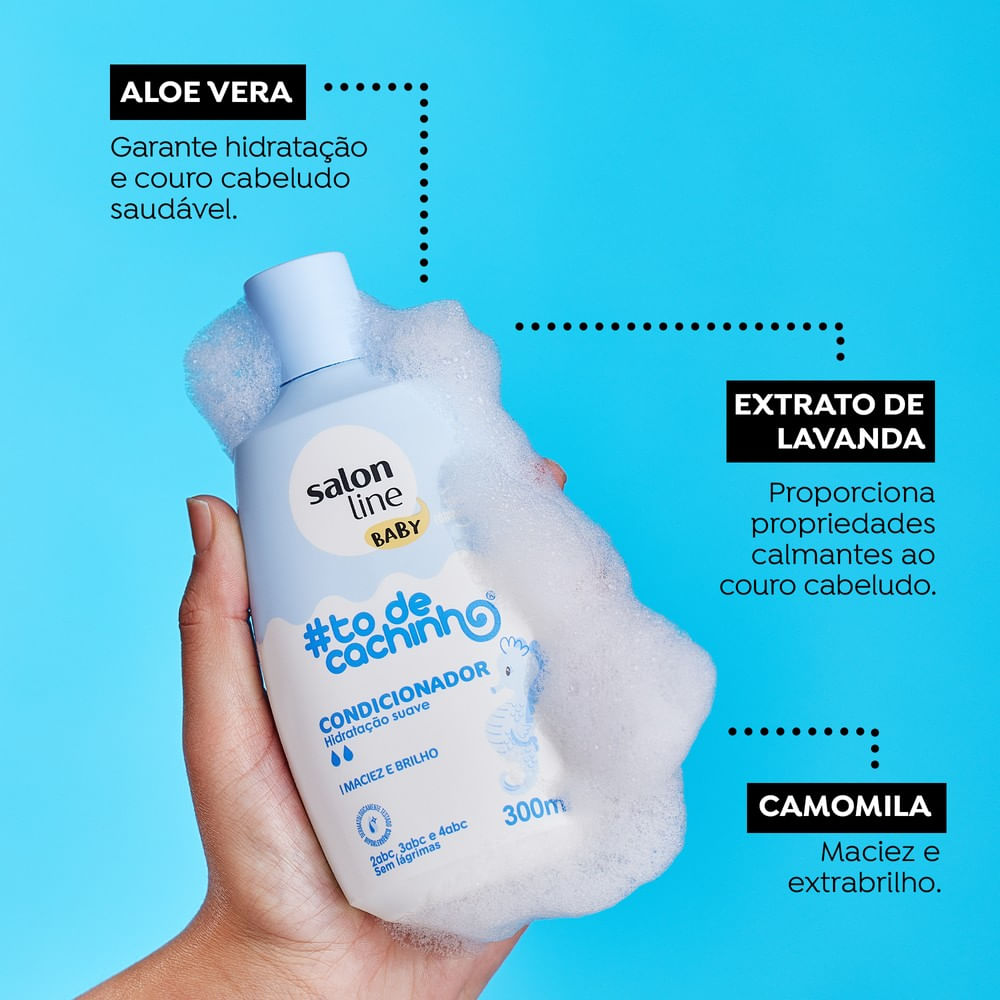 Mão segurando embalagem do condicionador Salon Line #todecachinho Baby com espuma