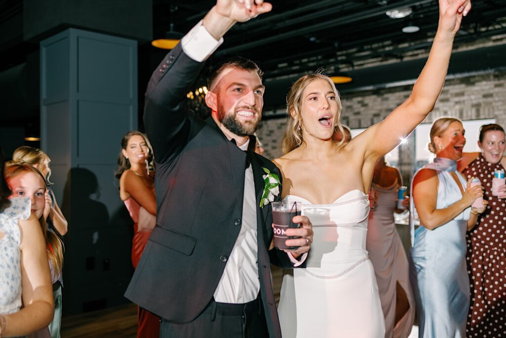 Vibrant wedding celebration with joyful couple and guests dancing and having fun indoors.