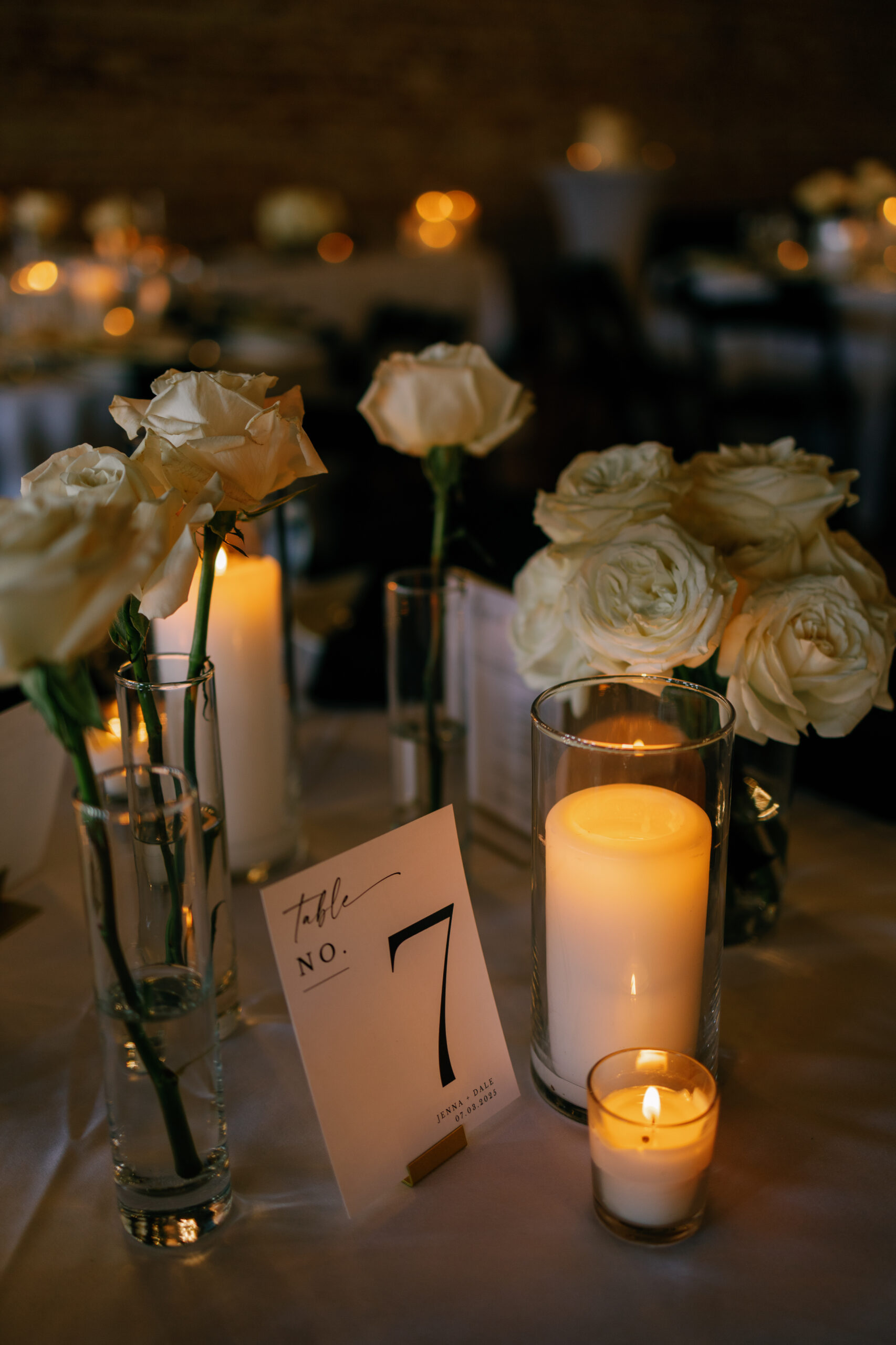 white candles and long stem white rose bud vase centerpiece