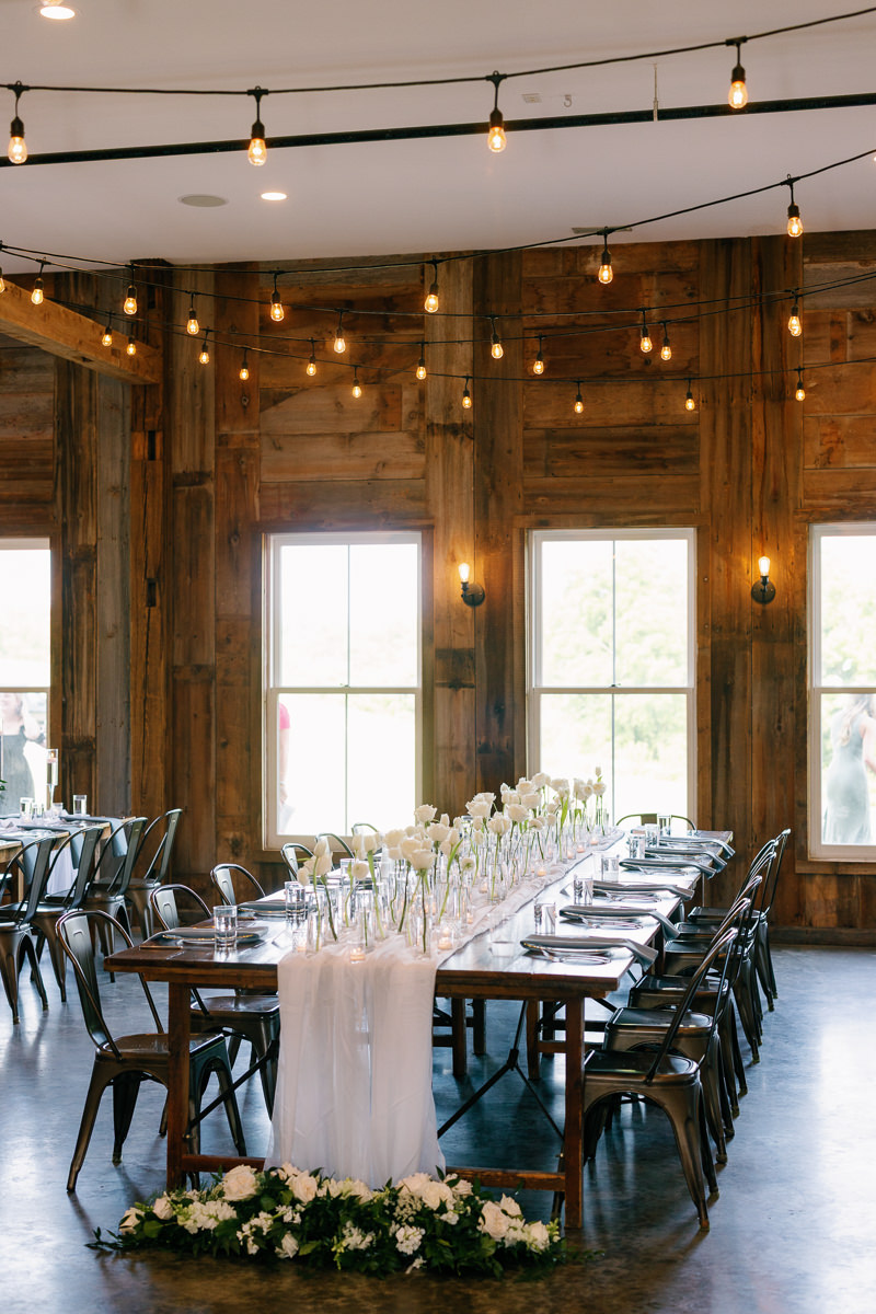 White rose bud vase cluster floral runner on kings table at reception at Wilsons Cidery