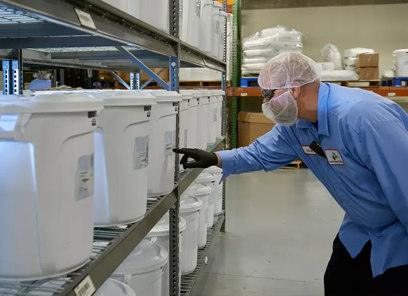 employee reviewing buckets of material in a production environment