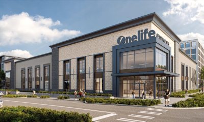 Rendering of a two-story stone and glass Onelife Fitness building on a street corner at Midtown64