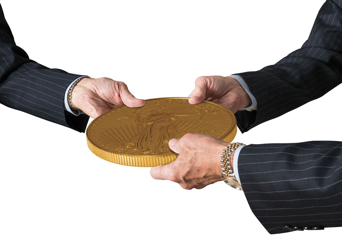 Hands of three financial traders gripping large Gold American Eagle coin