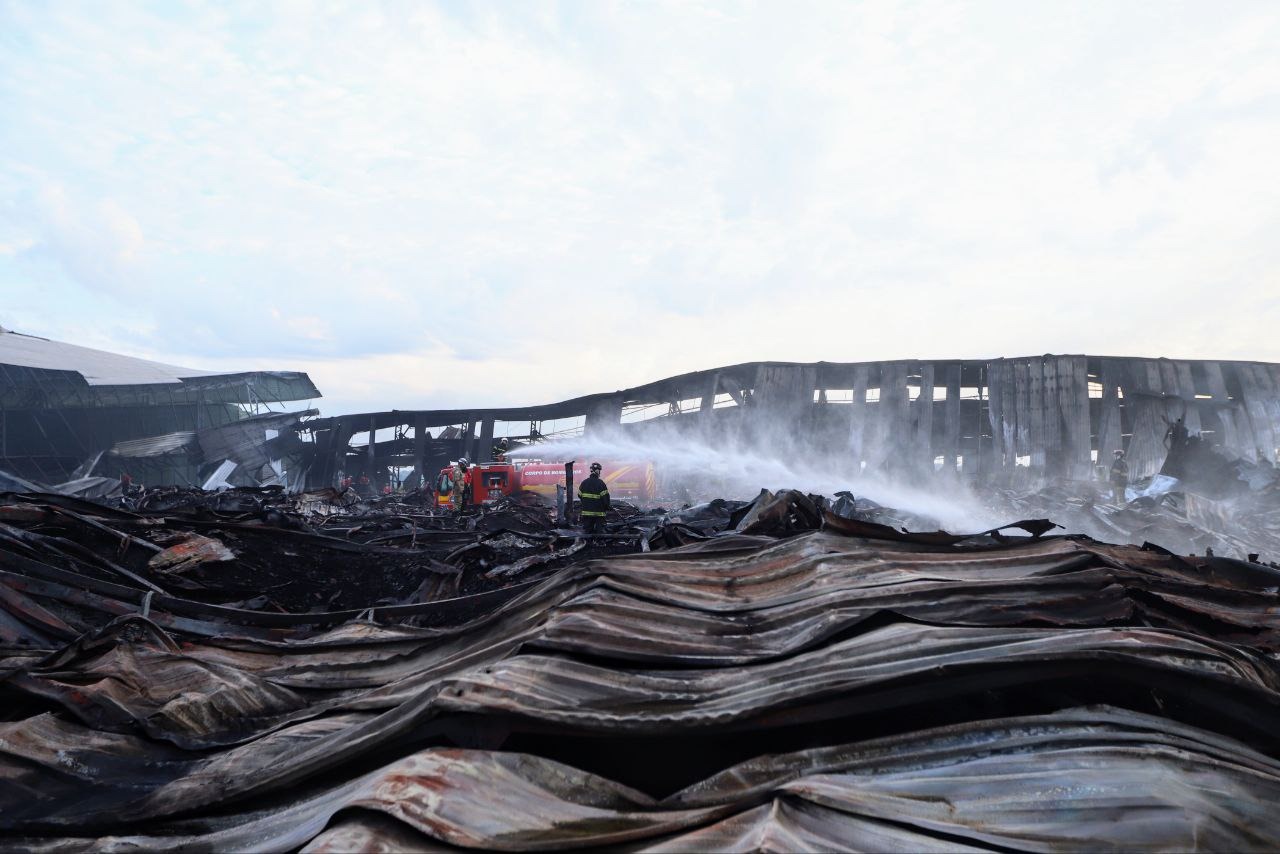 Bombeiros fazem rescaldo de  incêndio em fábrica com remoção dos entulhos queimados
