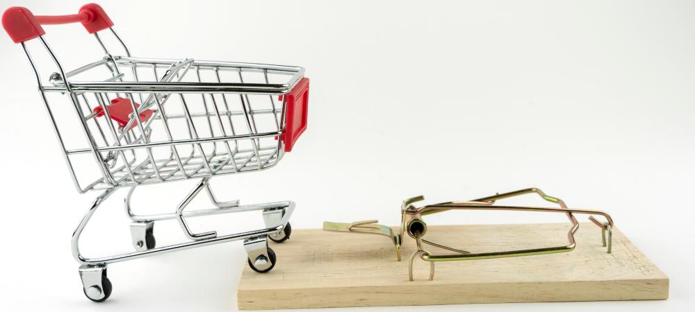 mini shopping cart standing on top of a mouse trap on a white background