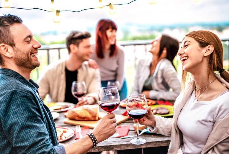 group of happy people laughing and eating on a restaurant patio