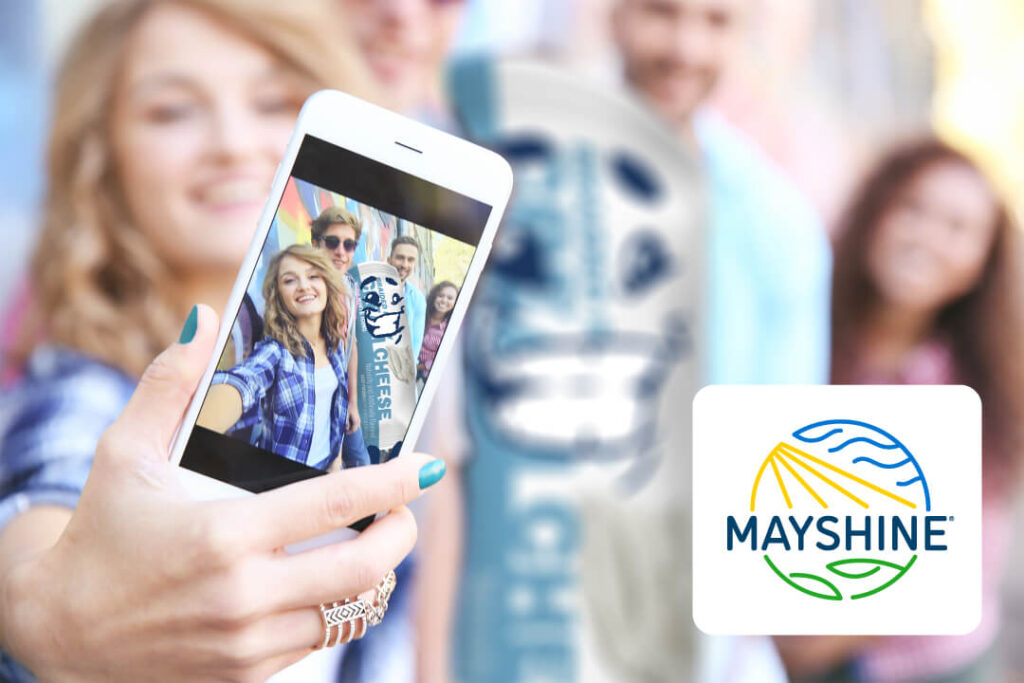 A group of high school students taking a selfie with a Cream Cheese Pastry Pal. They're outside enjoying the spring weather.