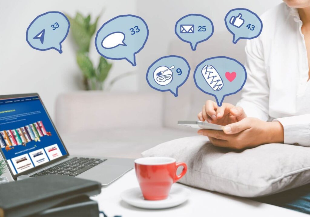 Person sitting with their computer and smartphone. Above the smartphone are several speech bubbles showing notification alerts for messages, social media, etc.