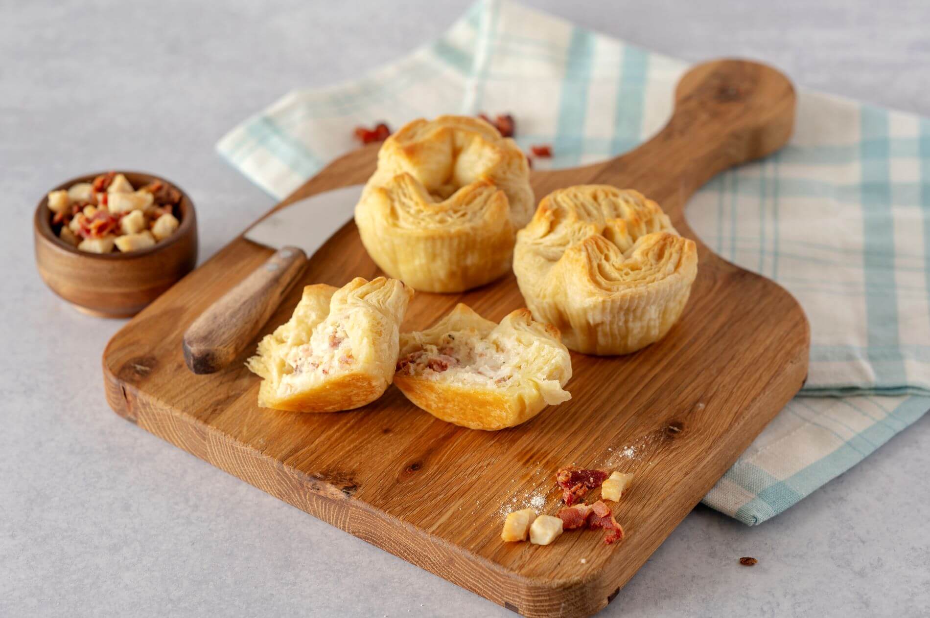 Three Chicken Bacon Ranch Croissant Crowns on a wood cutting board. One of the crowns is cut in half.