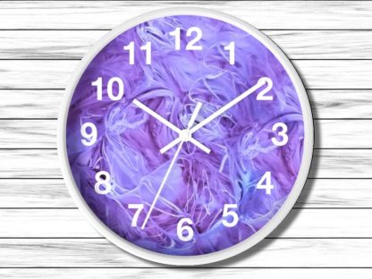 A round wall clock with a white frame features abstract swirls of purple and blue. The clock hands point to 10 and 2, set against a wood panel background.