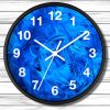 A round clock with a black frame features a vibrant blue swirl pattern face. White numerals and hands contrast against a wooden background.