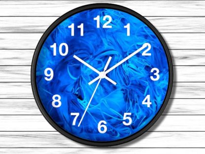 A round clock with a black frame features a vibrant blue swirl pattern face. White numerals and hands contrast against a wooden background.
