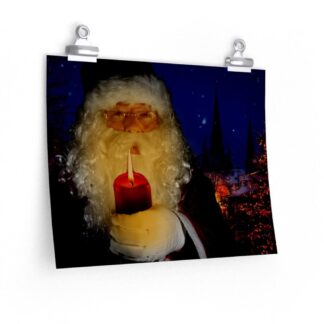 A framed picture on a blue wall shows Santa Claus holding a red candle against a nighttime Christmas scene with lit trees and church spires. An orange couch is in the foreground.