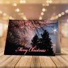 A Christmas card with "Merry Christmas" over a winter sky is open, revealing a heartfelt message inside. Nearby are candy canes and pine sprigs on a wooden surface.