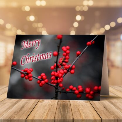 Christmas card on wooden surface with candy canes and pine. Closed card shows red berries with "Merry Christmas" text; inside has a red ribbon design.