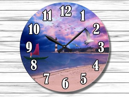 A clock with black numbers and hands features a serene seaside scene. The background has a pink and purple sky, birds flying, a lighthouse, and a boat with a red sail.