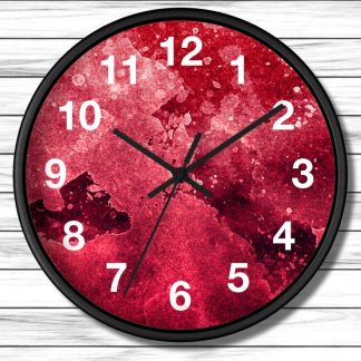 A round clock with a black frame and white numbers. The face has a textured, abstract red pattern. The time is 10:10. Background: white wooden planks.
