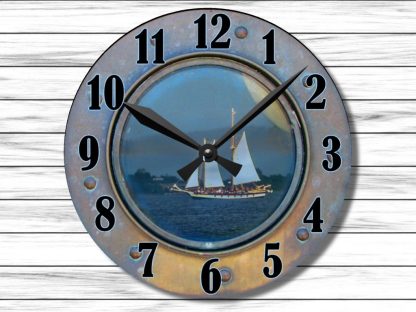 Rustic clock with a porthole design featuring a sailing ship on calm waters. Black numerals and hands contrast against a wooden background.