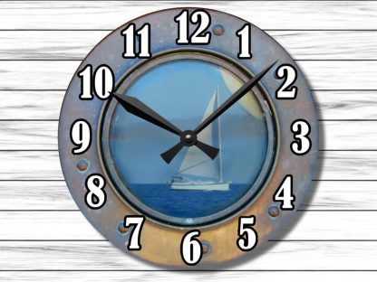 Rusted porthole clock with bold black numbers and hands. The face shows a serene sailboat on a blue sea, evoking nautical adventure. White wood background.