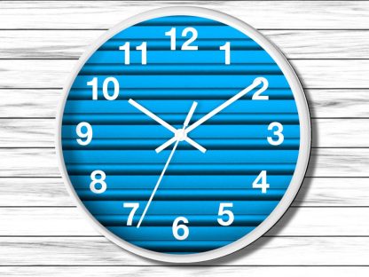 Wall clock with a white frame and bold white numerals on a blue striped background. The hands point to 10:10, conveying a clean, modern style.
