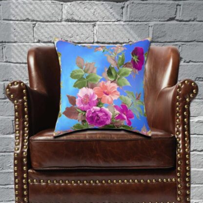 Blue pillow with vibrant floral design featuring pink and purple blossoms and green leaves. The colors convey a cheerful, lively tone.