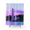 Shower curtain featuring a lighthouse and adjacent house at sunset, with a sky awash in pink and purple hues. Calm water and trees complete the scene.