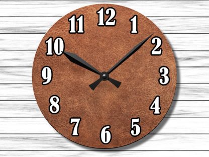 A round wall clock with a textured brown face and bold black and white numbers on a light wood background. The clock shows 10:10.