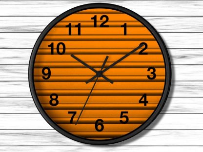 A round wall clock with a black frame features an orange, textured background. Black numbers and hands indicate the time, showing approximately 10:10.