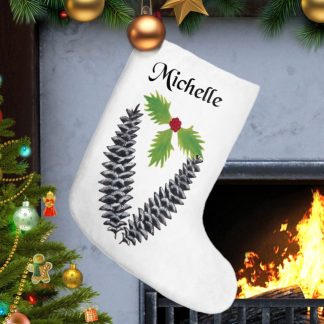 A festive Christmas scene with a white personalized stocking, adorned with pine cones and holly, hanging by a lit fireplace. A decorated Christmas tree glows nearby.