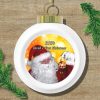 A white Christmas ornament on a wood texture background, featuring a smiling Santa holding a mini Santa ornament. Text reads "2024 Sarah's First Christmas." Pine branches accent the corners.