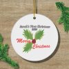 Round Christmas ornament on wood with "Sarah's First Christmas 2024" in black and "Merry Christmas" in red. Decorated with green holly leaves and red berries.