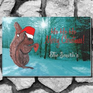 A festive holiday welcome mat features a squirrel in a red Santa hat standing on snowy ground against a blue-toned forest. Red text reads "Ho Ho Ho Merry Christmas!" and white text says "The Smith's."