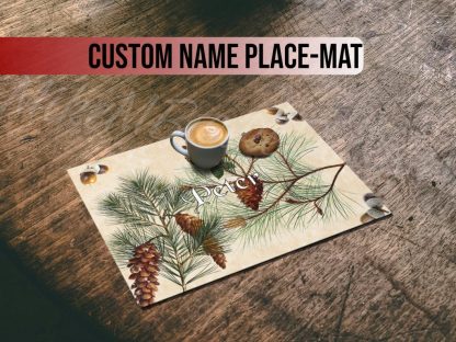 A latte and cookie sit on a placemat with pine branches and acorns on a rustic wooden table. The ambiance is cozy and inviting.