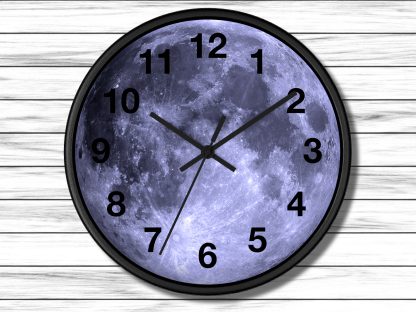 A round wall clock with a full moon face set against white wood panels. The clock hands point to 10:10, evoking a serene, celestial theme.