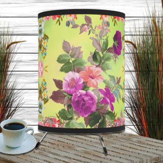 Floral-patterned yellow lampshade on a wooden table with a cup of coffee. Background features tall grass decor against a white-paneled wall.