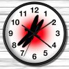 A wall clock with bold black numbers on a white face. The center features a black dragonfly silhouette against a bright red circle, creating contrast.
