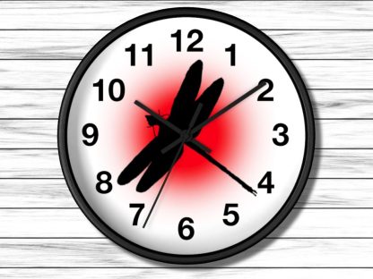 A wall clock with bold black numbers on a white face. The center features a black dragonfly silhouette against a bright red circle, creating contrast.