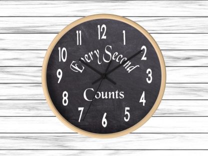 A round wall clock with a wooden frame and black chalkboard face displays white numbers. The text "Every Second Counts" is written diagonally across the center. The background is light wooden planks, creating a rustic feel.